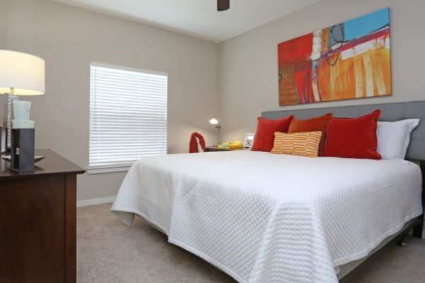 Bedroom with plush carpeting, king bed, window, dresser, night stands, and ceiling fan
