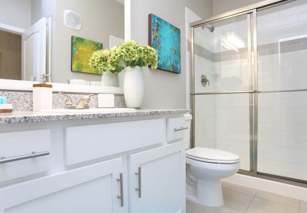 Bathroom with ceramic tile flooring, walk in shower, large vanity with a granite countertop and white cabinets, and toilet