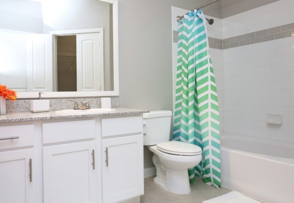 Bathroom with ceramic tile flooring, large vanity, toilet, and shower bath