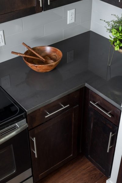 Close up of the dark quartz kitchen countertop with a wooden bowl and two salad spoons resting on top