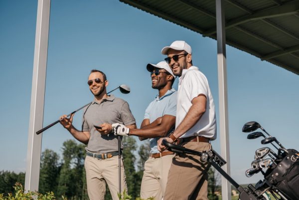 Three men smiling and holding golf clubs