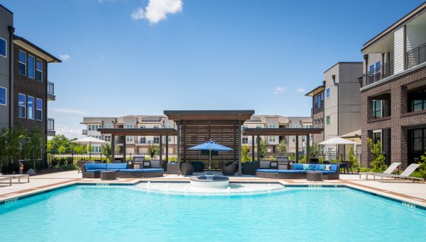 Sparkling, blue pool and surrounding sundeck with lounge chairs, couches, cabanas, and grilling stations