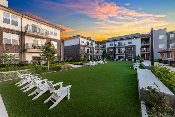 Large, open turf area in front of the apartment homes with Adirondack chairs at sunset