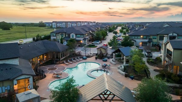 Aerial shot of the Lake Walk community with one of the pools at the center and a beautiful orange sunset in the sky