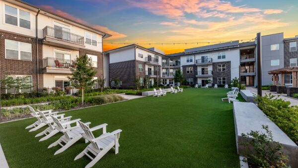 Large, open turf area in front of the apartment homes with Adirondack chairs at sunset